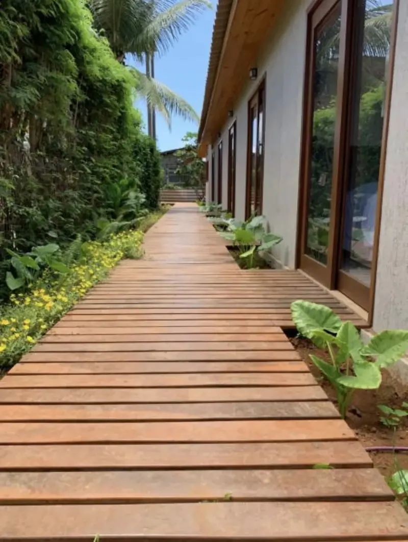 Passarela de madeira com jardim tropical na Pousada Maresia
